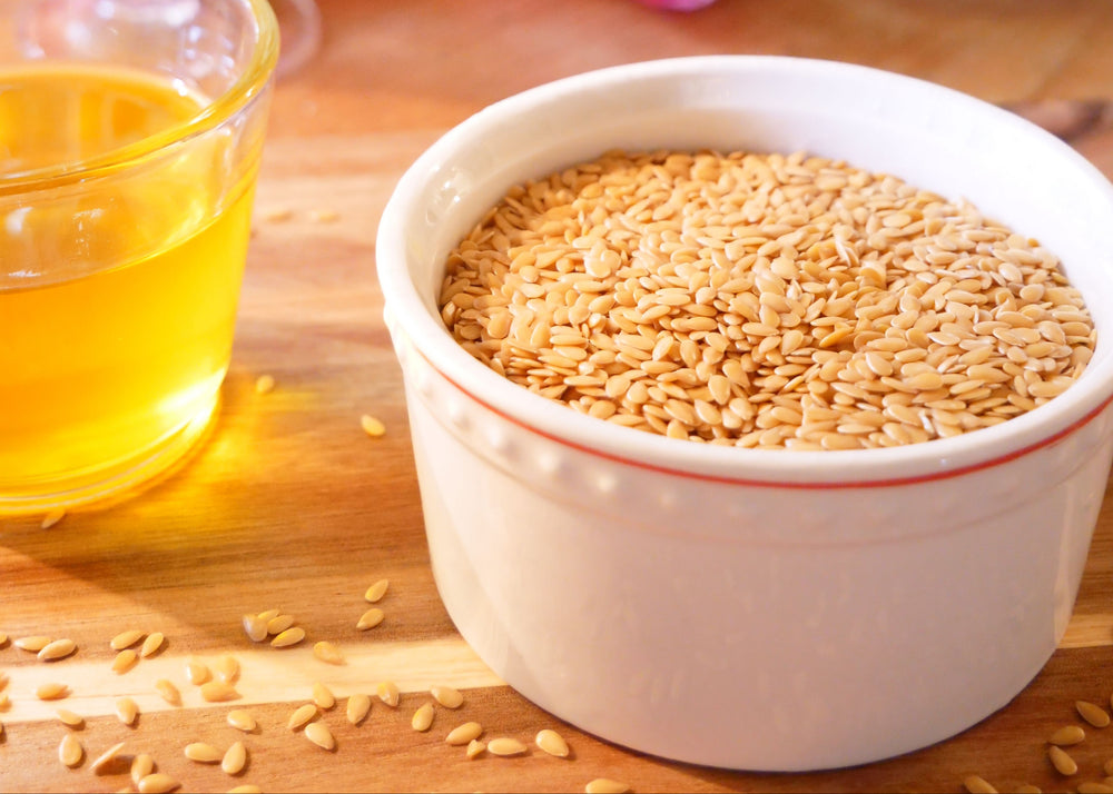 Bowl of sesame seeds beside a glass of sesame oil